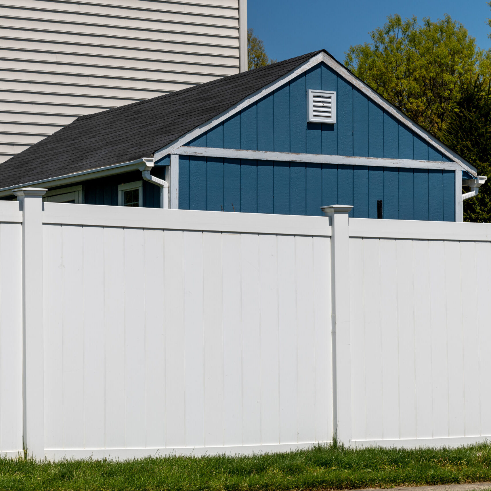 white vinyl picket fence on green lawn surrounding property grounds for backyard protection and privacy wall